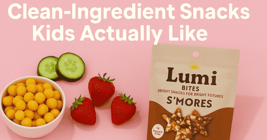 Clean-ingredient kids snacks including a Lumi Bites S’mores snack pouch with fresh strawberries, cucumber slices, and crunchy snack bites on a soft pink background.